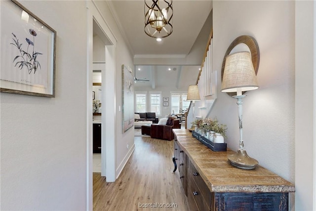 hallway featuring crown molding, light hardwood / wood-style flooring, and an inviting chandelier