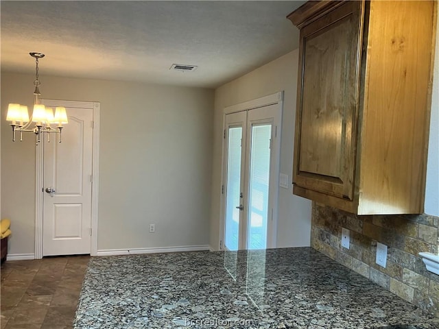 kitchen featuring a notable chandelier, french doors, and tasteful backsplash