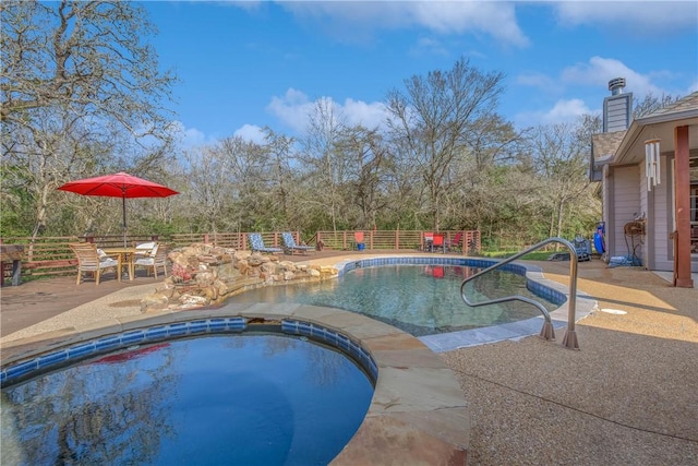 view of swimming pool featuring fence, a pool with connected hot tub, and a patio area