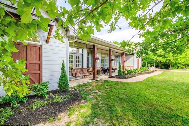 exterior space with a ceiling fan, a patio area, french doors, and a lawn