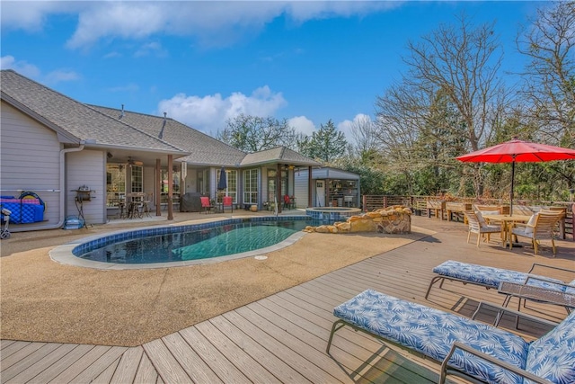 view of swimming pool featuring outdoor dining area, a pool with connected hot tub, a patio, a wooden deck, and ceiling fan