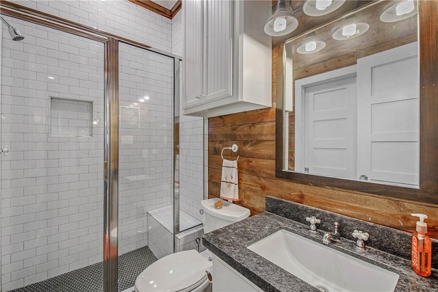 bathroom featuring vanity, toilet, a stall shower, and wood walls