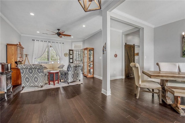 interior space featuring crown molding, ceiling fan, baseboards, a barn door, and wood finished floors