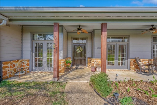 entrance to property with french doors, stone siding, and a ceiling fan