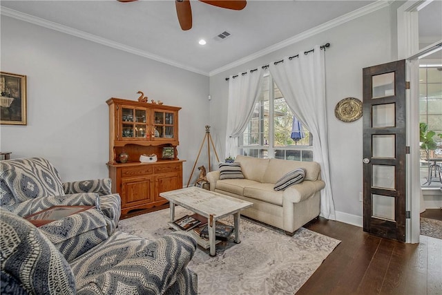 living room featuring visible vents, baseboards, ornamental molding, wood finished floors, and a ceiling fan