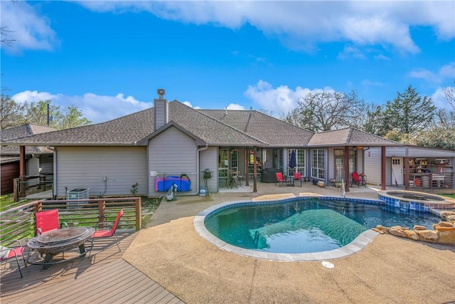 view of swimming pool with a patio area, a fire pit, and a pool with connected hot tub