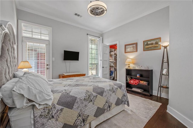 bedroom featuring a walk in closet, multiple windows, dark wood-style floors, and visible vents