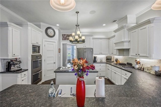 kitchen featuring stainless steel appliances, white cabinets, a notable chandelier, tasteful backsplash, and a center island