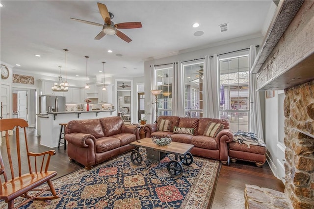 living area with visible vents, recessed lighting, dark wood-style flooring, ornamental molding, and ceiling fan with notable chandelier