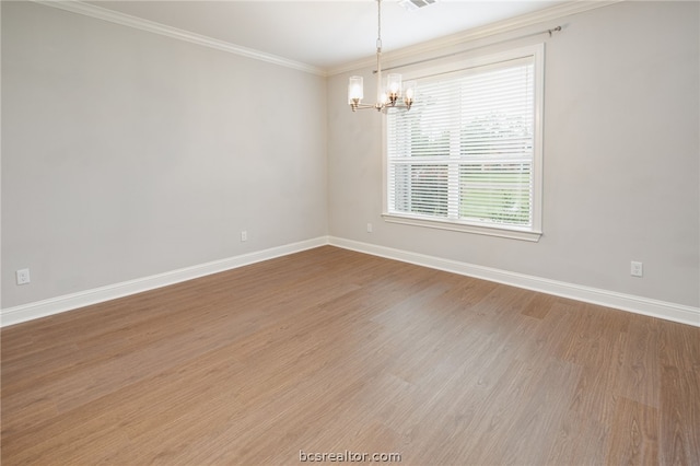 empty room with crown molding, hardwood / wood-style floors, and an inviting chandelier