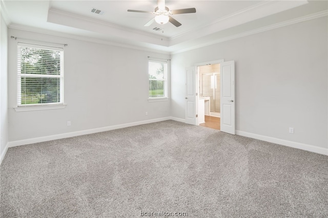 carpeted empty room featuring ornamental molding, a tray ceiling, baseboards, and a ceiling fan