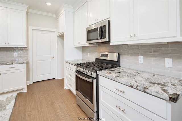 kitchen featuring light stone counters, white cabinets, stainless steel appliances, and light hardwood / wood-style floors