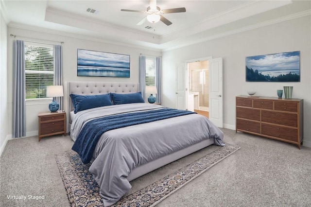 bedroom with light carpet, a tray ceiling, baseboards, and crown molding