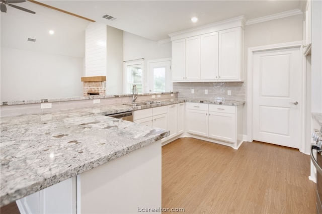 kitchen with white cabinets, light stone counters, light hardwood / wood-style flooring, and sink