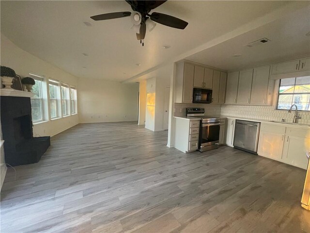 15933 Goliad Loop, Temple, TX 76502 - kitchen with appliances with stainless steel finishes, a sink, open floor plan, a fireplace with raised hearth, and wood finished floors