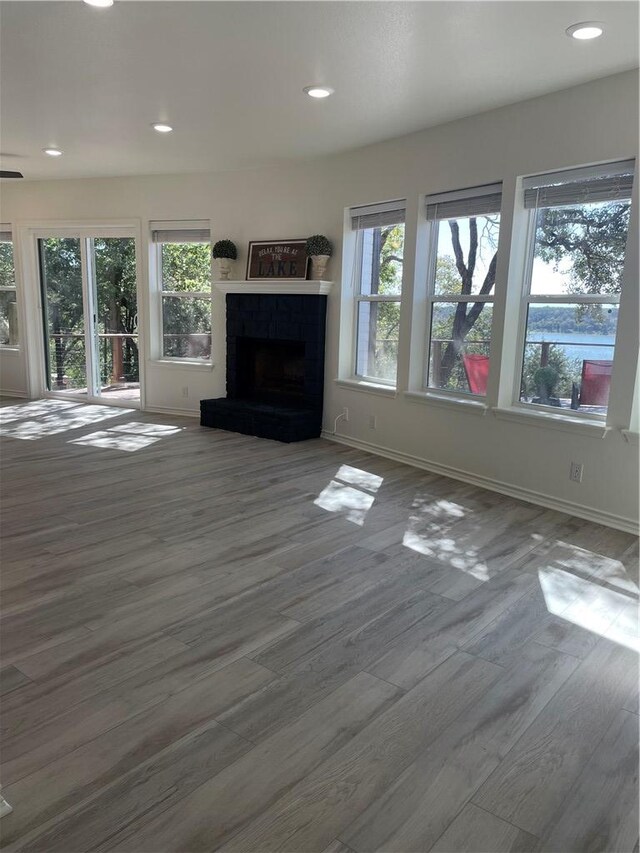15933 Goliad Loop, Temple, TX 76502 - unfurnished living room featuring wood finished floors, baseboards, a fireplace with raised hearth, and recessed lighting