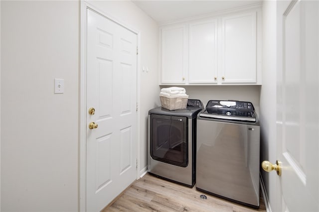 clothes washing area with washer and dryer, light wood finished floors, and cabinet space