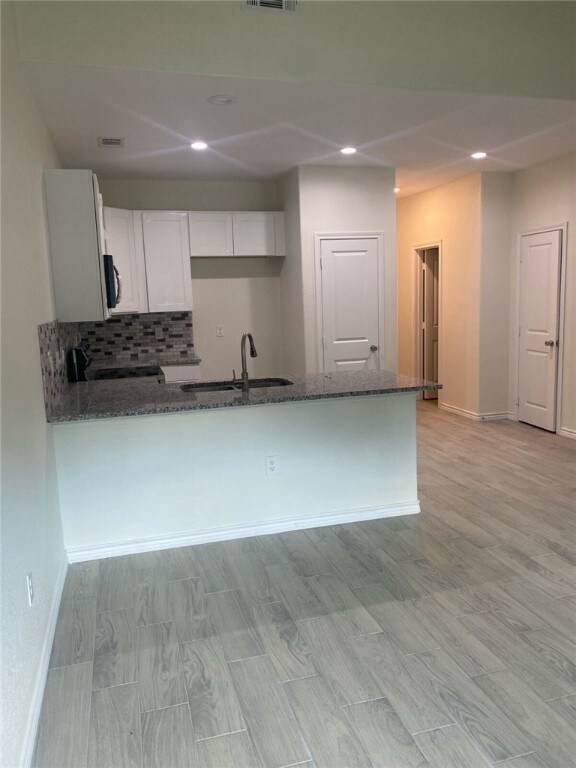 kitchen with white cabinetry, dark stone countertops, and kitchen peninsula