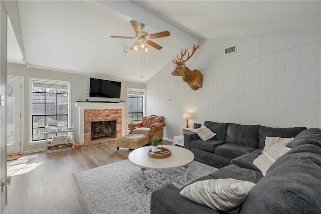 living room with hardwood / wood-style flooring, ceiling fan, a fireplace, and lofted ceiling with beams