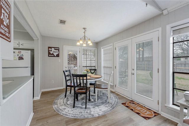 dining area featuring a notable chandelier, light hardwood / wood-style flooring, and french doors