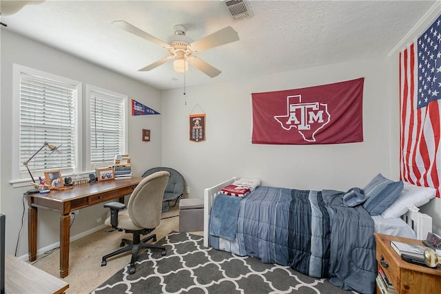 carpeted bedroom with ceiling fan and a textured ceiling