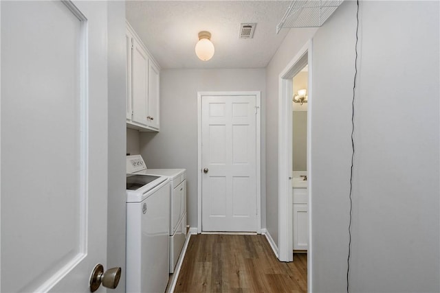 laundry area with cabinets, separate washer and dryer, a textured ceiling, and light wood-type flooring