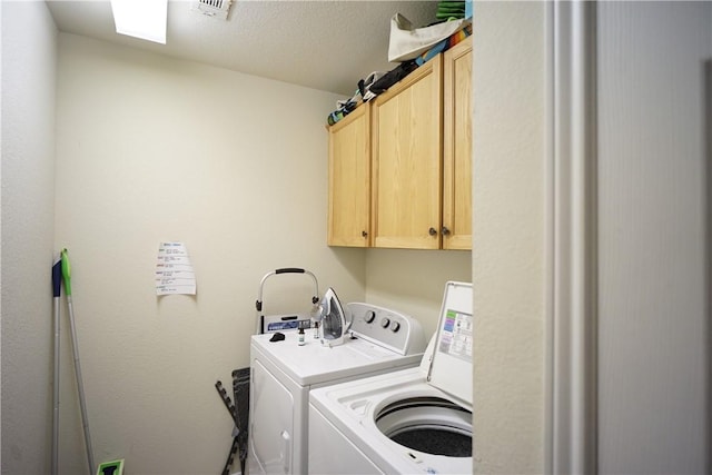 washroom with cabinet space, visible vents, washer and clothes dryer, and a textured ceiling