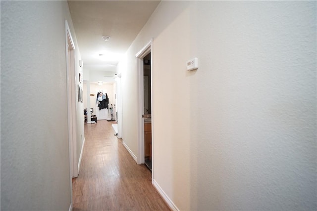 corridor with wood finished floors and baseboards