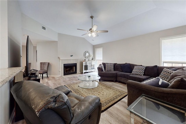 3900 Puffin Way, College Station, TX 77845 - living area with vaulted ceiling, light wood-style flooring, a ceiling fan, a tiled fireplace, and baseboards