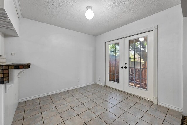 interior space with french doors, light tile patterned flooring, and a textured ceiling