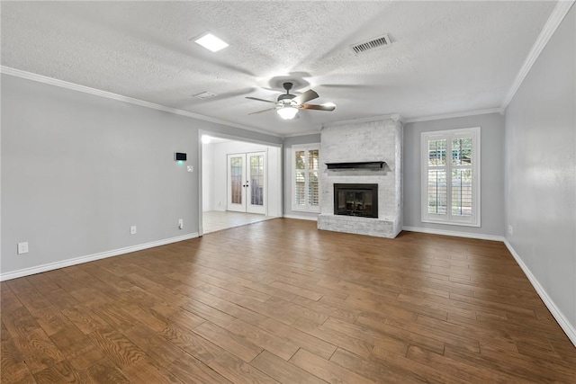 unfurnished living room with ceiling fan, a brick fireplace, wood-type flooring, a textured ceiling, and ornamental molding