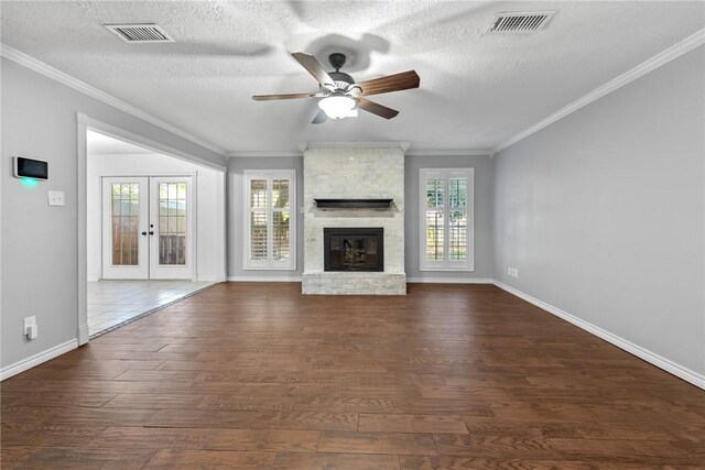 unfurnished living room featuring crown molding, french doors, a textured ceiling, and a brick fireplace