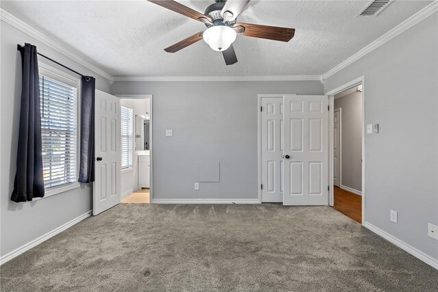 unfurnished bedroom with ensuite bathroom, crown molding, ceiling fan, a textured ceiling, and light colored carpet