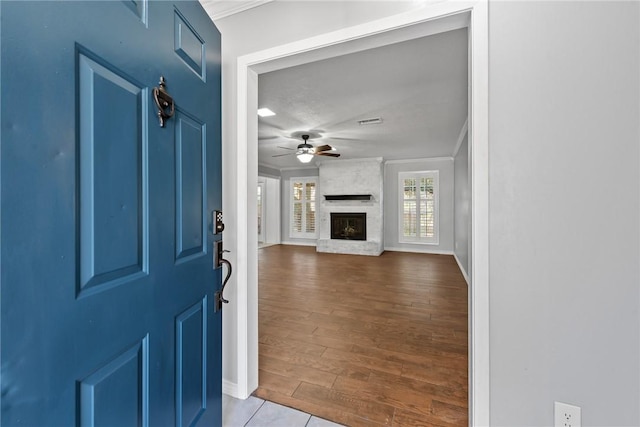 living room with hardwood / wood-style floors, ceiling fan, ornamental molding, and a brick fireplace