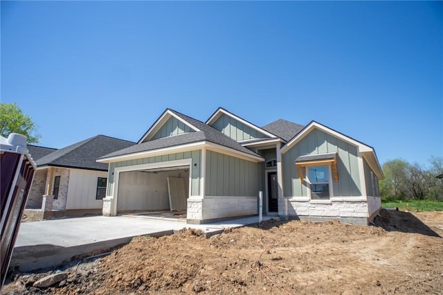 2581 Dove Xing, Navasota, TX 77868 - view of front facade with stone siding, an attached garage, board and batten siding, roof with shingles, and driveway