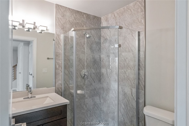 bathroom featuring vanity, toilet, and a shower with shower door