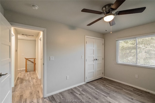 unfurnished bedroom with ceiling fan, light wood-type flooring, and a closet