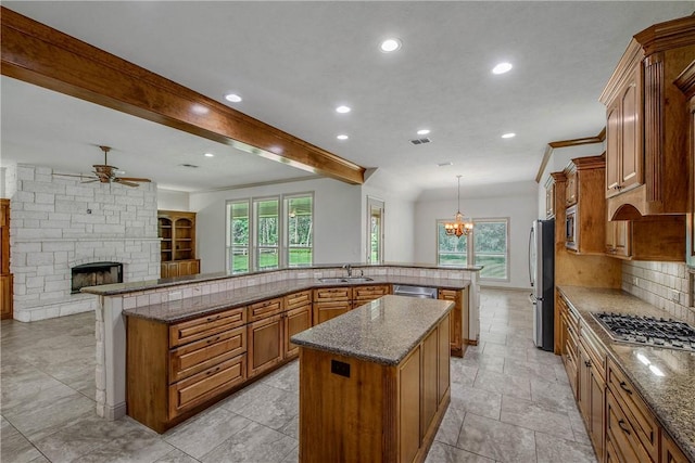 4662 Hidden Springs Way, College Station, TX 77845 - kitchen with appliances with stainless steel finishes, a spacious island, brown cabinets, a sink, and a ceiling fan