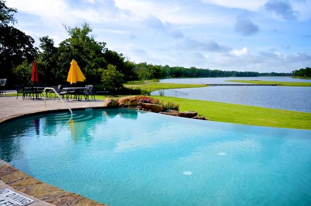 3719 Tatonga Trl, College Station, TX 77845 - view of pool with a water view, a patio area, an infinity pool, and a lawn