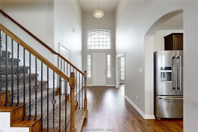 entryway with dark hardwood / wood-style floors and a towering ceiling