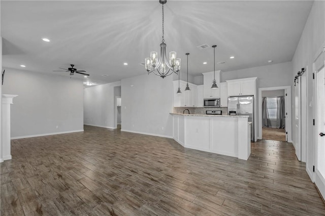 kitchen featuring appliances with stainless steel finishes, ceiling fan with notable chandelier, dark wood-type flooring, white cabinets, and hanging light fixtures