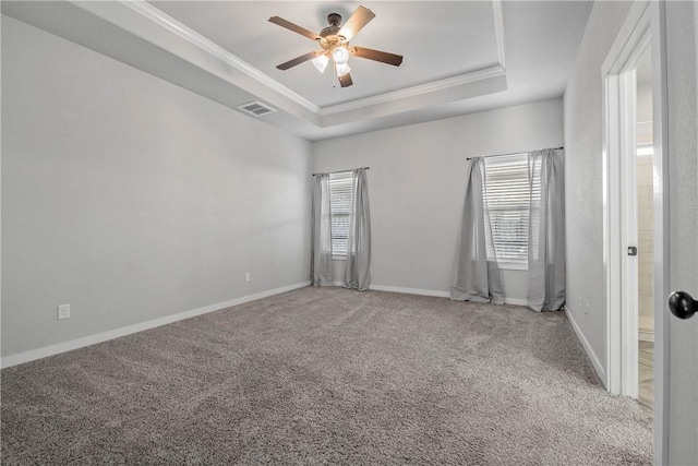 carpeted empty room with a tray ceiling, ceiling fan, a healthy amount of sunlight, and ornamental molding