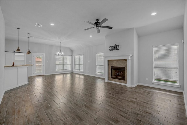 unfurnished living room featuring a wealth of natural light, a fireplace, and ceiling fan with notable chandelier