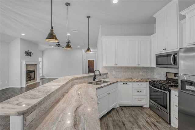 kitchen featuring white cabinetry, sink, stainless steel appliances, and decorative light fixtures