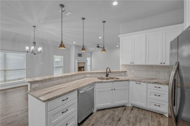 kitchen with backsplash, stainless steel appliances, sink, decorative light fixtures, and white cabinetry