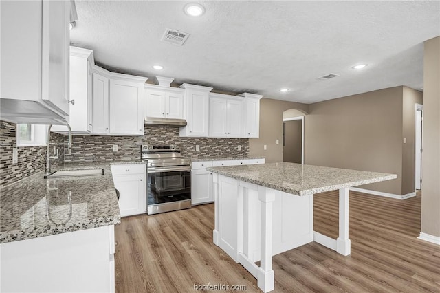 508 N O Neal St, Caldwell, TX 77836 - kitchen with a center island, white cabinets, light hardwood / wood-style floors, and stainless steel electric range