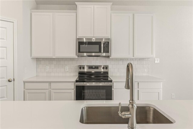 kitchen with decorative backsplash, stainless steel appliances, white cabinetry, and sink