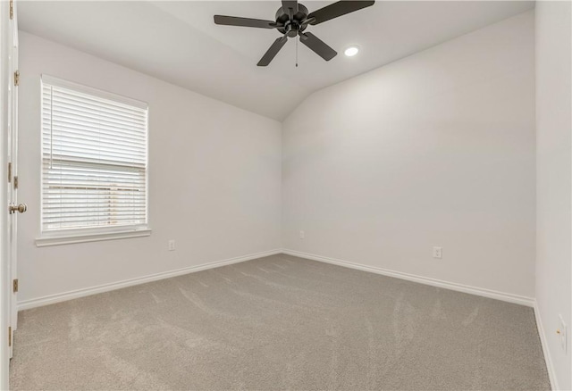 carpeted spare room featuring vaulted ceiling and ceiling fan