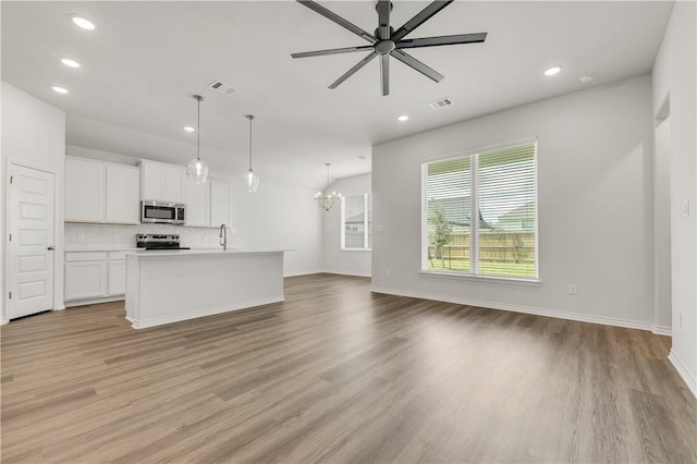 unfurnished living room featuring light hardwood / wood-style flooring, ceiling fan with notable chandelier, and sink