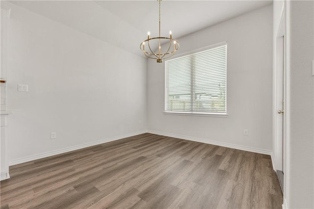 unfurnished room with hardwood / wood-style floors and a notable chandelier